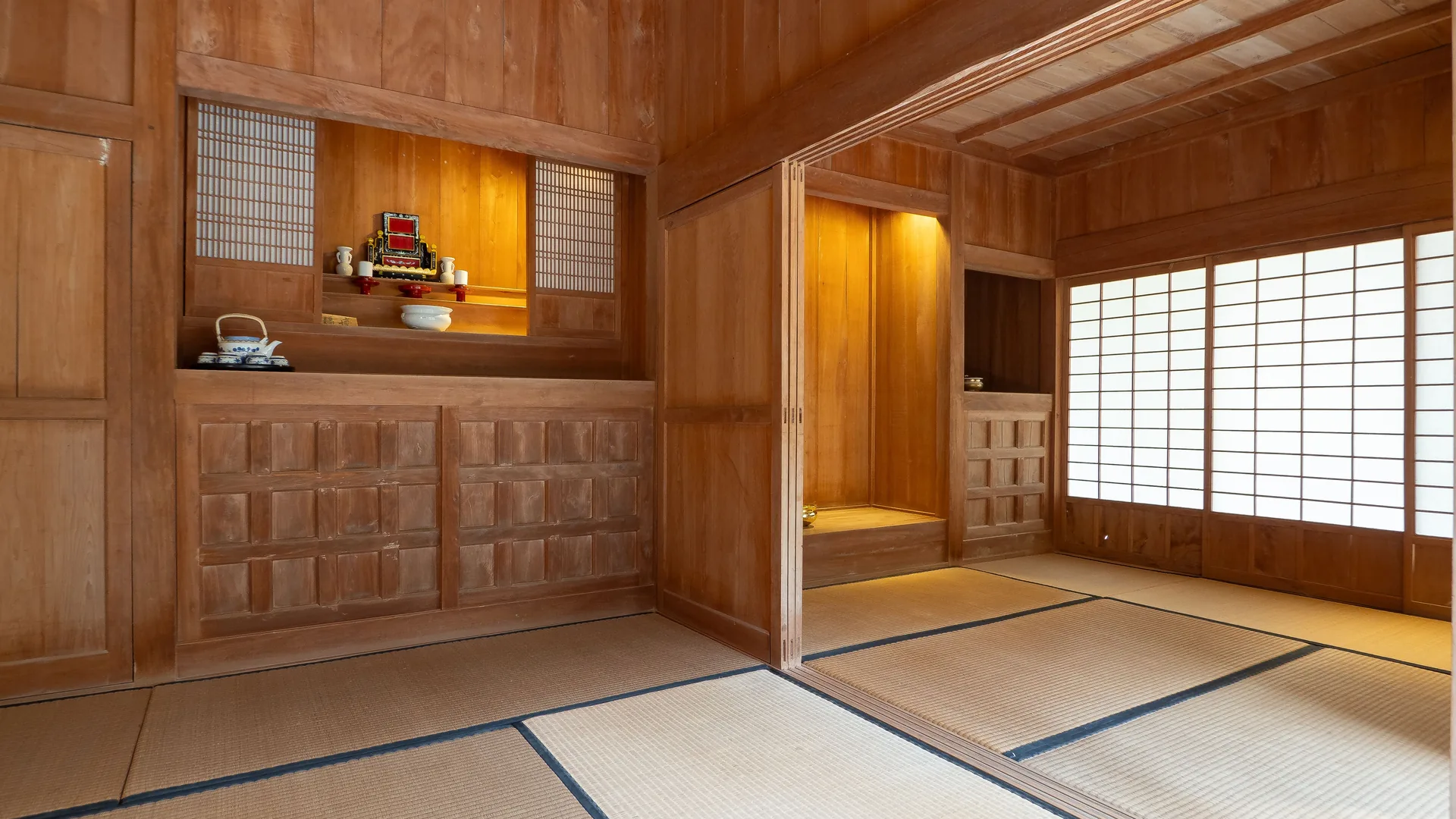 A traditional Japanese room with dark wood panelling, tatami floors and paper shoji screens
